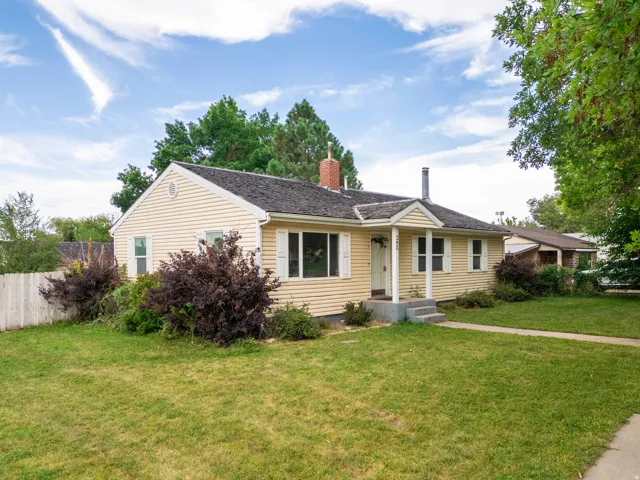 Ranch-style exterior with horizontal siding, a covered porch entry, a brick chimney, and a picket fence