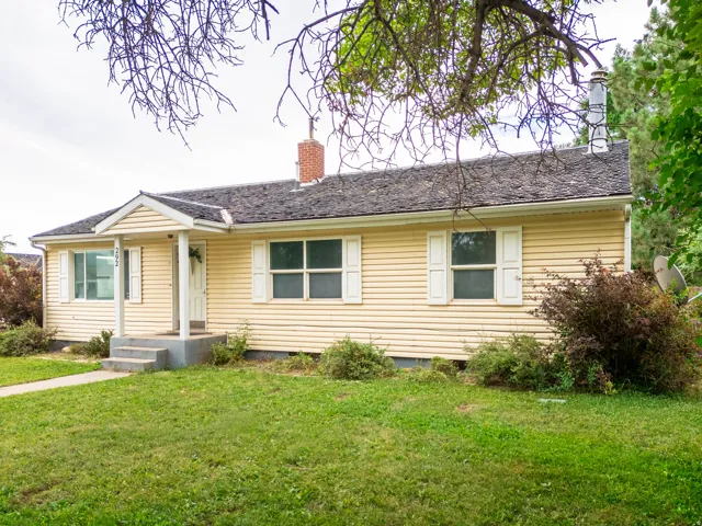 Exterior featuring yellow siding, white window shutters, and a covered porch entry