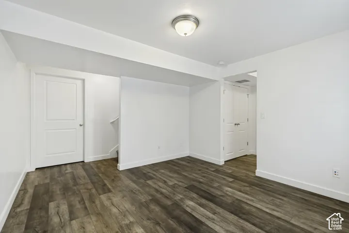 Spacious room with wood-finish flooring throughout, multiple white six-panel doors, recessed ceiling lighting, and neutral wall finishes providing flexible layout options