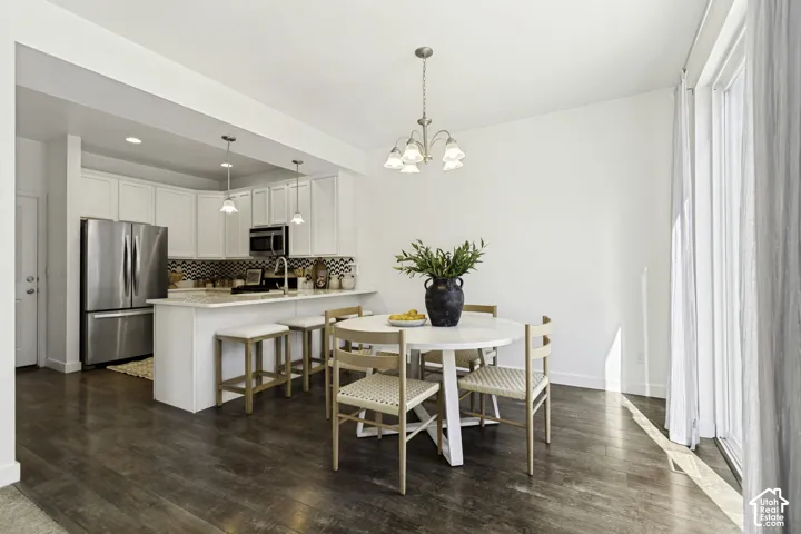Kitchen with stainless steel appliances, white cabinetry, a kitchen island with seating, and wood-finish flooring
