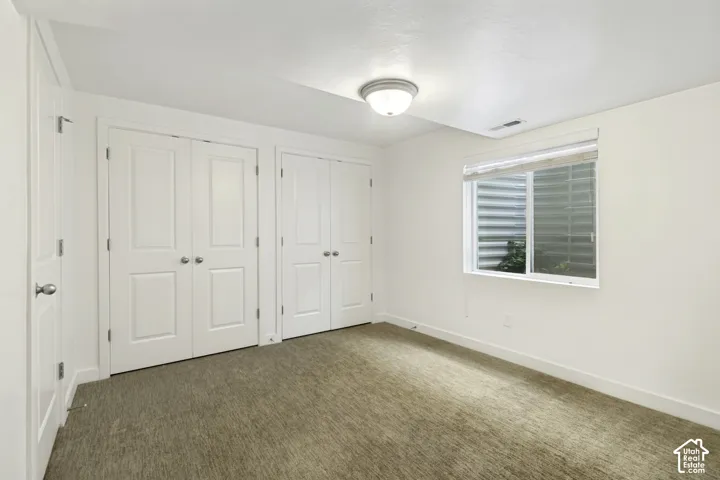 Recessed window with blinds, overhead flush-mount lighting, and light-colored carpeting