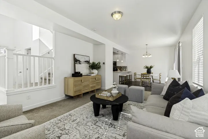 Open-concept living area with neutral wall tones, carpeted flooring, and a white staircase with baluster railing