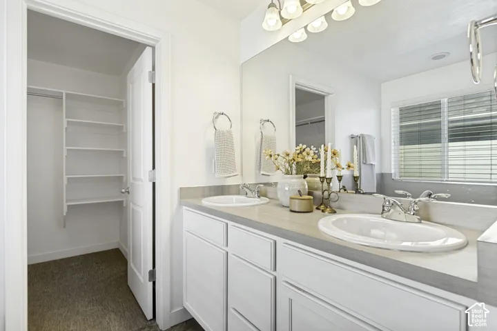 Dual vanity with white cabinetry and integrated sinks, wide mirror, and built-in closet shelving