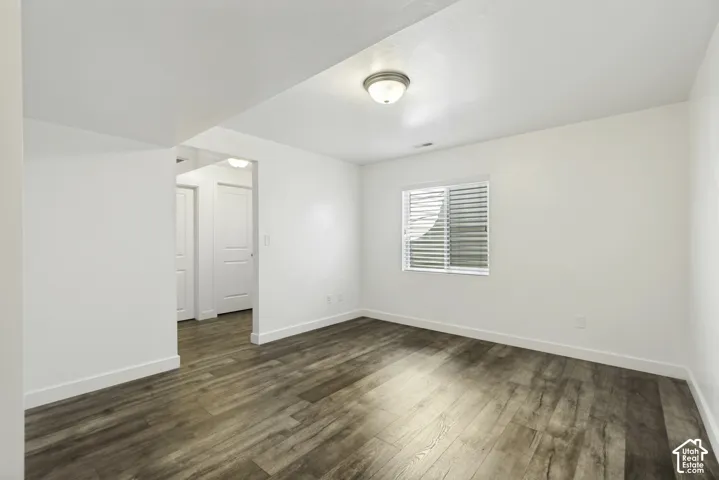 Wood-finish flooring, white walls, white trim, recessed lighting, and a single window with blinds