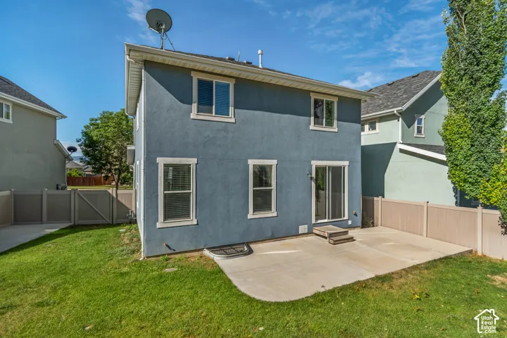 Stucco exterior with multiple windows and a sliding glass door leading to a concrete patio
