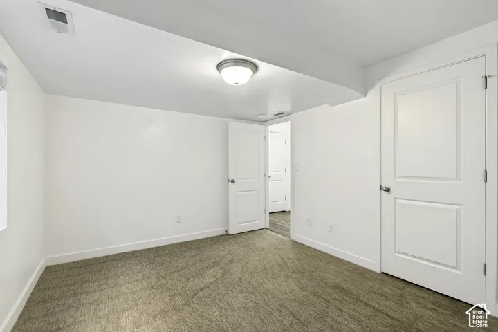 Spacious bedroom with warm wood-finish flooring, white six-panel doors, and abundant natural light from multiple windows