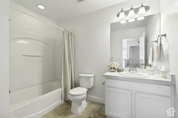 White vanity with a single basin sink and chrome faucet, large frameless mirror, three-light vanity fixture, white toilet, and a white bathtub with shower