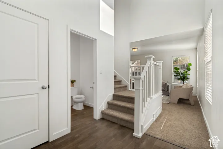 High ceilings with recessed lighting, staircase with white newel posts and carpeted treads, wood-finish flooring, and white interior doors