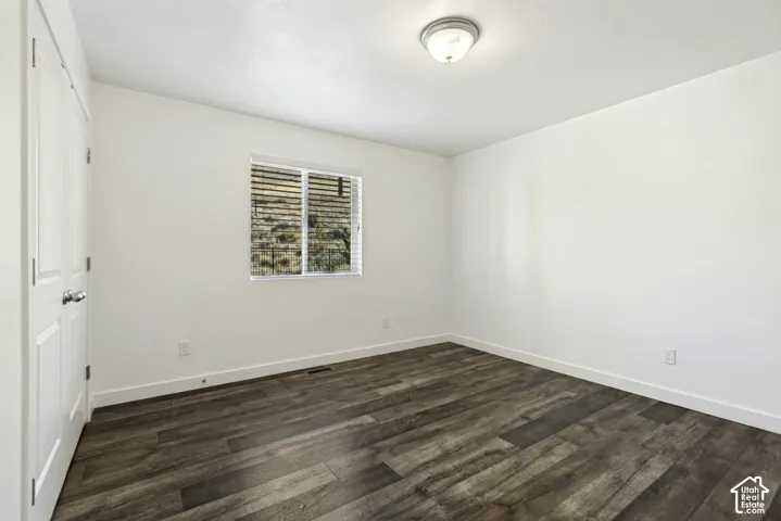 Wood-finish flooring with white baseboards, a window with horizontal blinds, and a flush mount ceiling light fixture