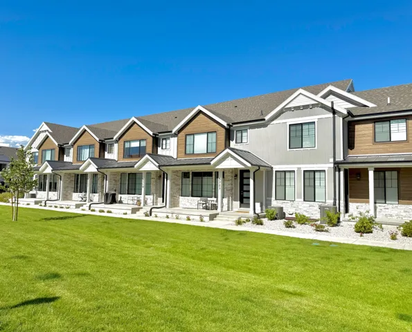 Modern townhome exterior with mixed material facade, white stone accents, dark frame windows, and covered front entryways