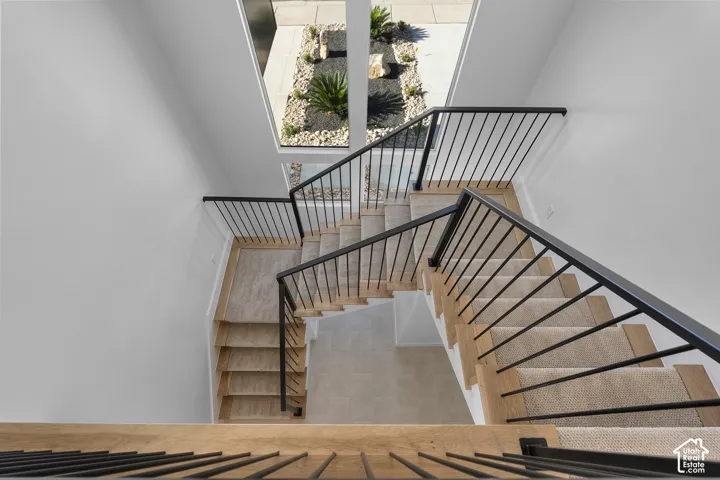 Wood-finish staircase with carpeted treads and black metal railings