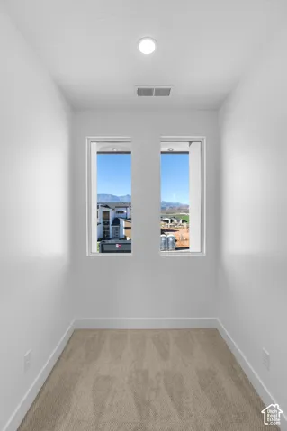 Bright, light-filled hallway featuring dual French doors with expansive glass panes framing mountain vistas, recessed ceiling lighting, and wood-finish flooring throughout