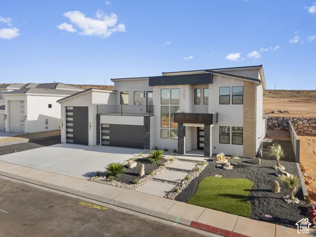 Contemporary exterior with a two-car garage, stone accents, and a second-story balcony