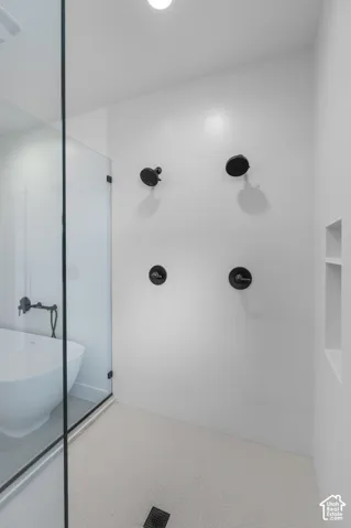 Walk-in shower with black-finish fixtures, a built-in storage niche, and hexagonal floor tiling