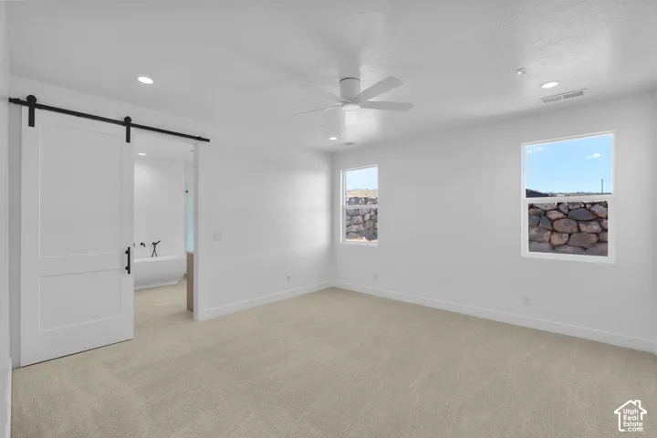 Spacious room with light-colored carpeting, white walls, and recessed lighting