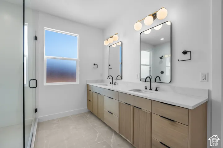 Spa-inspired primary bathroom featuring dual vanities with wood-finish cabinetry, white quartz countertops, and matte black faucetry