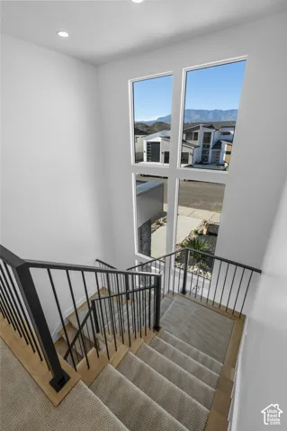 Staircase with light-toned carpet treads, wood-finish risers, and black metal balusters