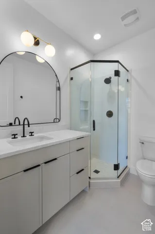 Vanity with integrated sink and matte black faucet, glass-enclosed shower with dark bronze fixtures, and arch-top mirror