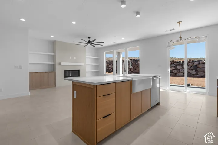 Open concept living area featuring a kitchen island with a farmhouse sink, white countertops, and wood-finish cabinetry