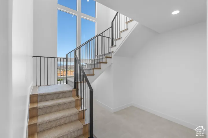 Staircase featuring wood-finish treads, carpeted risers, and black metal railings