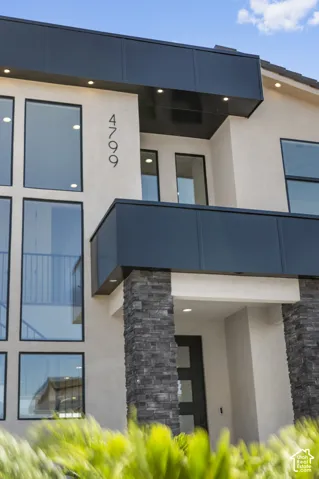 Modern exterior featuring large windows, a stone-clad column, an architectural facade, and a recessed entry