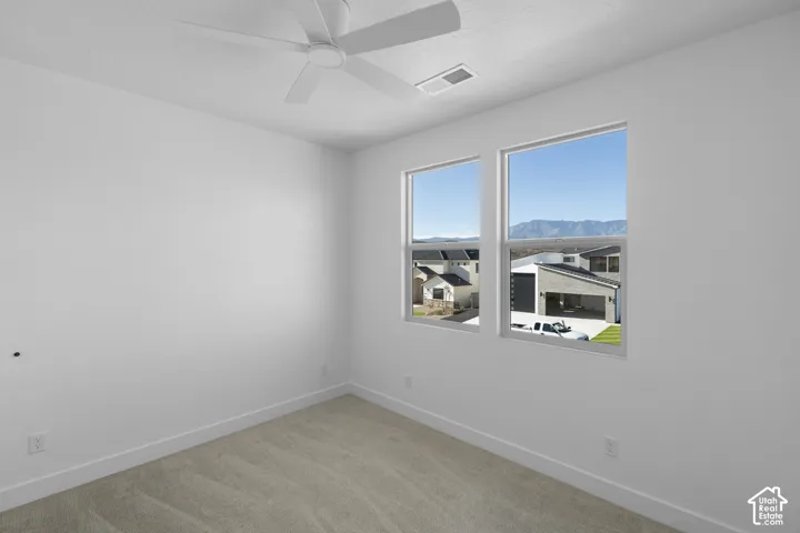 Bright room featuring two windows, a ceiling fan, and carpeting