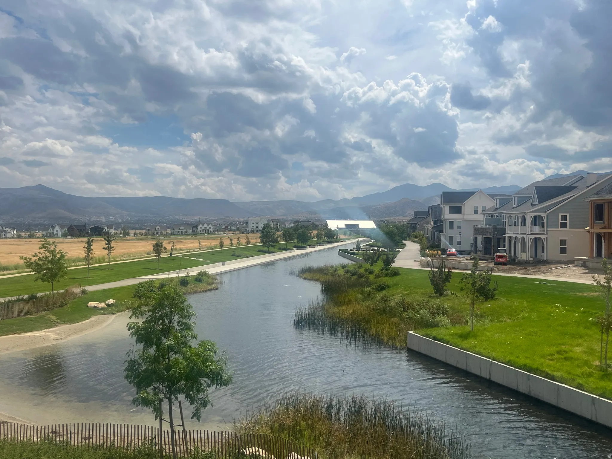 Waterfront property showcasing a serene canal-side setting with manicured lawn, mature landscaping, and established trees