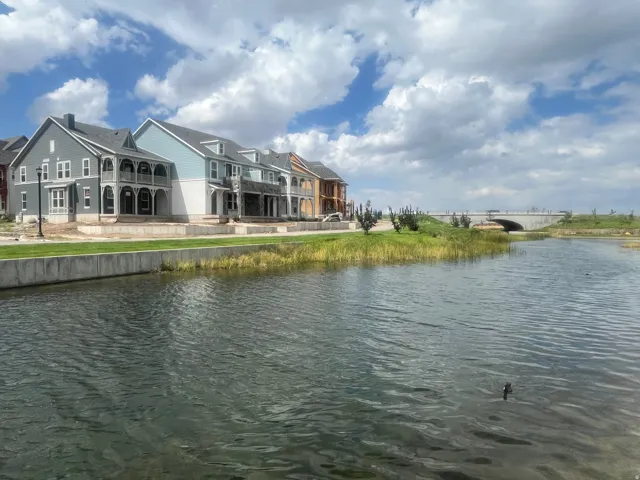 Waterfront property with multi-story facades, featuring balconies with decorative railings and a nearby bridge