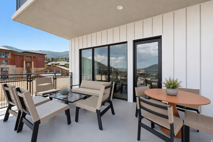 Outdoor patio featuring a black metal railing, a modern black frame sliding glass door, an additional black frame glass door, white vertical paneling, and a light-colored concrete floor