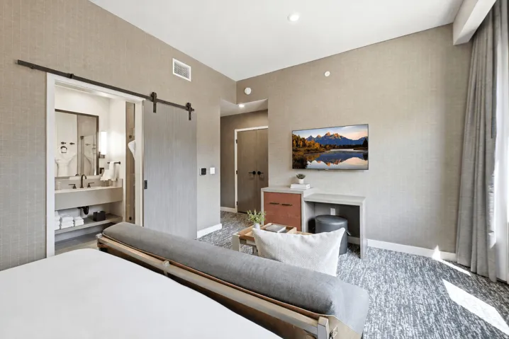 Wall-mounted television with built-in desk, wood-finish barn door, recessed lighting, and textured wall coverings