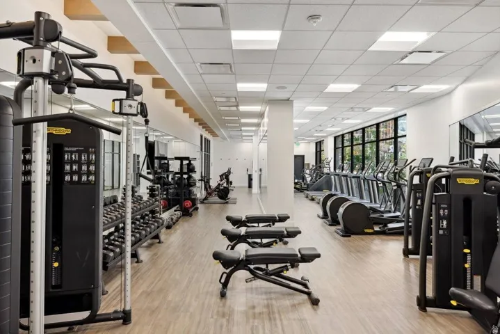 Spacious fitness center featuring wood-finish flooring, recessed lighting, expansive windows, and mirrored walls