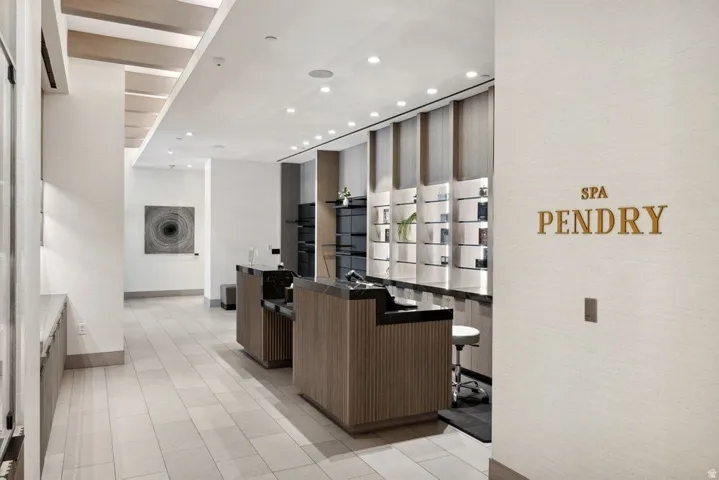Recessed lighting illuminating wood-finish slatted ceilings, a counter with a stone surface, and display shelving