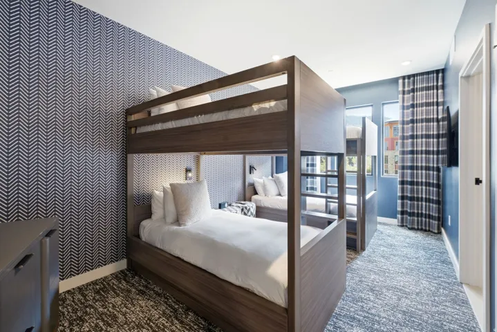 Built-in bunk beds with integrated lighting, patterned accent wallpaper, wall-to-wall carpeting, and multiple windows