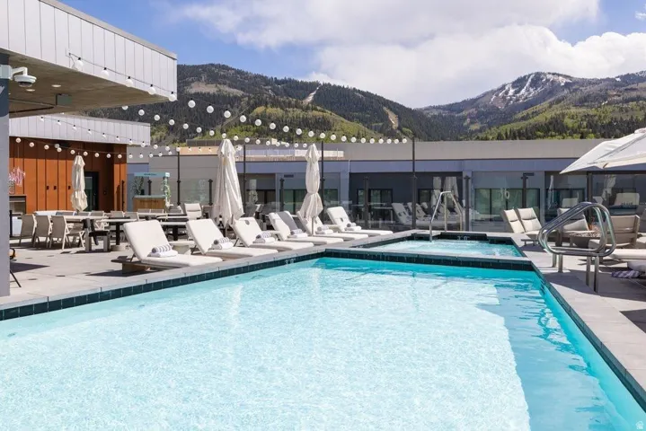Outdoor swimming pool with integrated spa and mountain backdrop, surrounded by a hardscape deck
