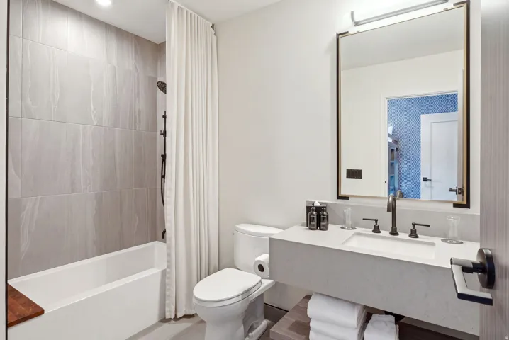 Modern bathroom with a floating vanity, single basin sink, and a framed mirror with integrated lighting