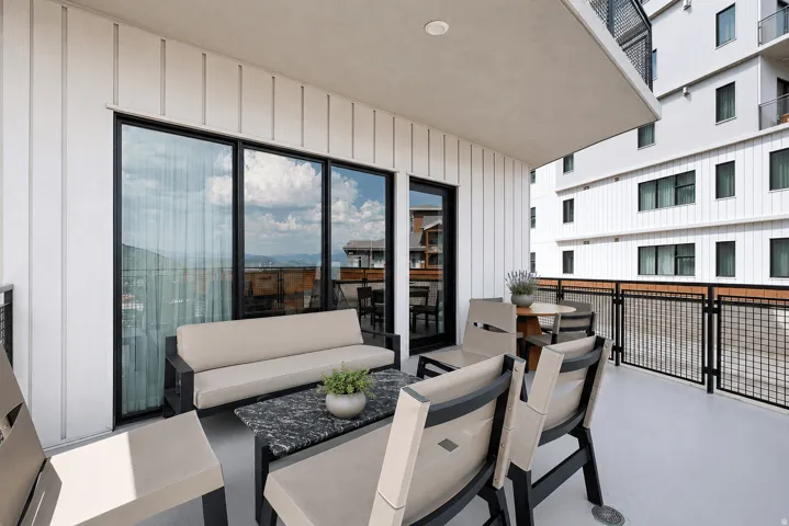 Contemporary rooftop terrace featuring floor-to-ceiling glass doors with black-frame detailing, polished concrete flooring, and metal railing