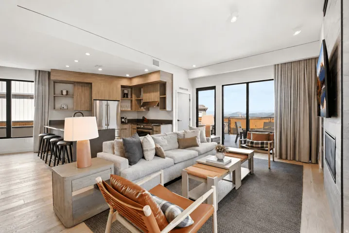 Open-concept living area featuring a gray upholstered sectional sofa, wood-finish coffee table, and cognac leather accent chair
