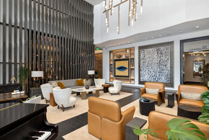 Spacious common area featuring a grand piano, a contemporary light fixture, and a decorative slatted wood wall