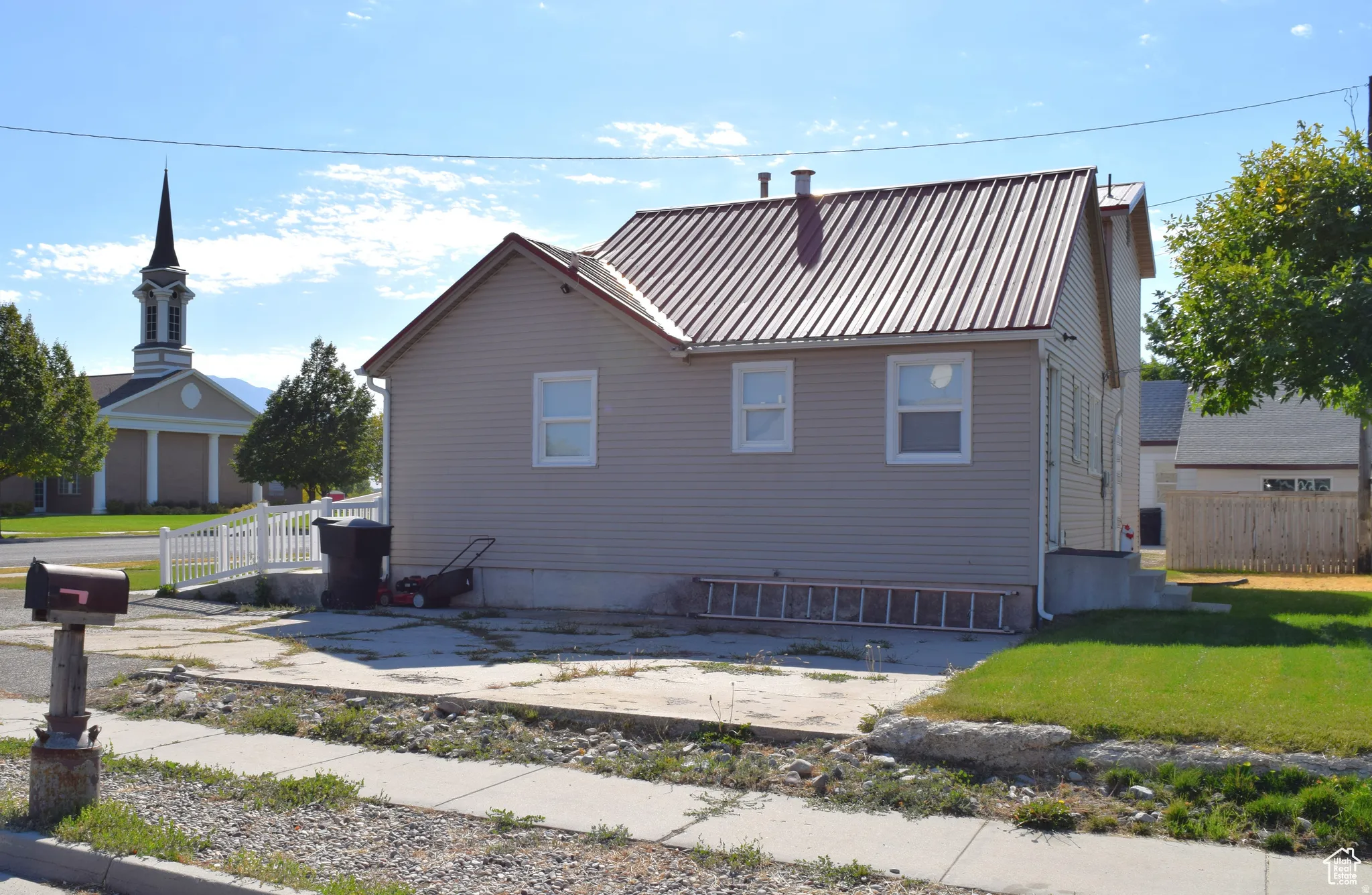 Charming residential home featuring a spacious front facade with multiple windows, standing seam metal roof, and vinyl siding exterior