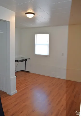 Wood-finish flooring, white paneled wainscoting, white walls, and a ceiling-mounted light fixture