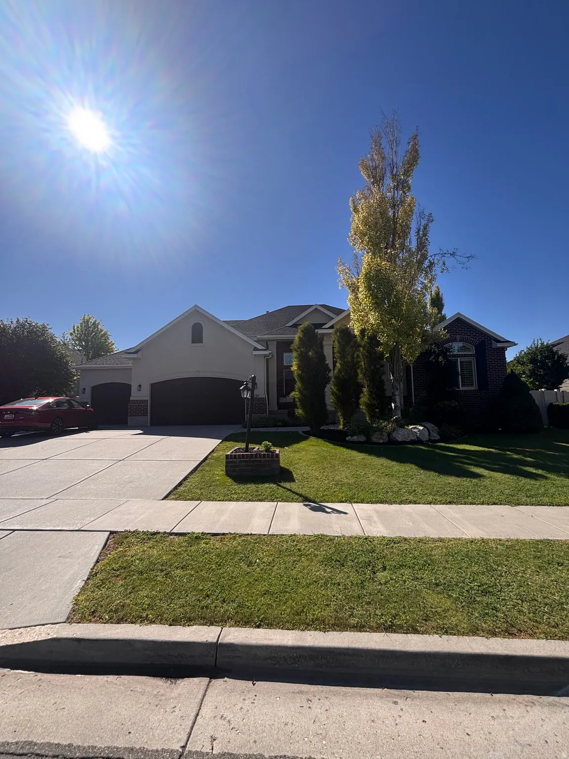 Stucco exterior, two-car garage, concrete driveway, established landscaping, and a street-facing lawn