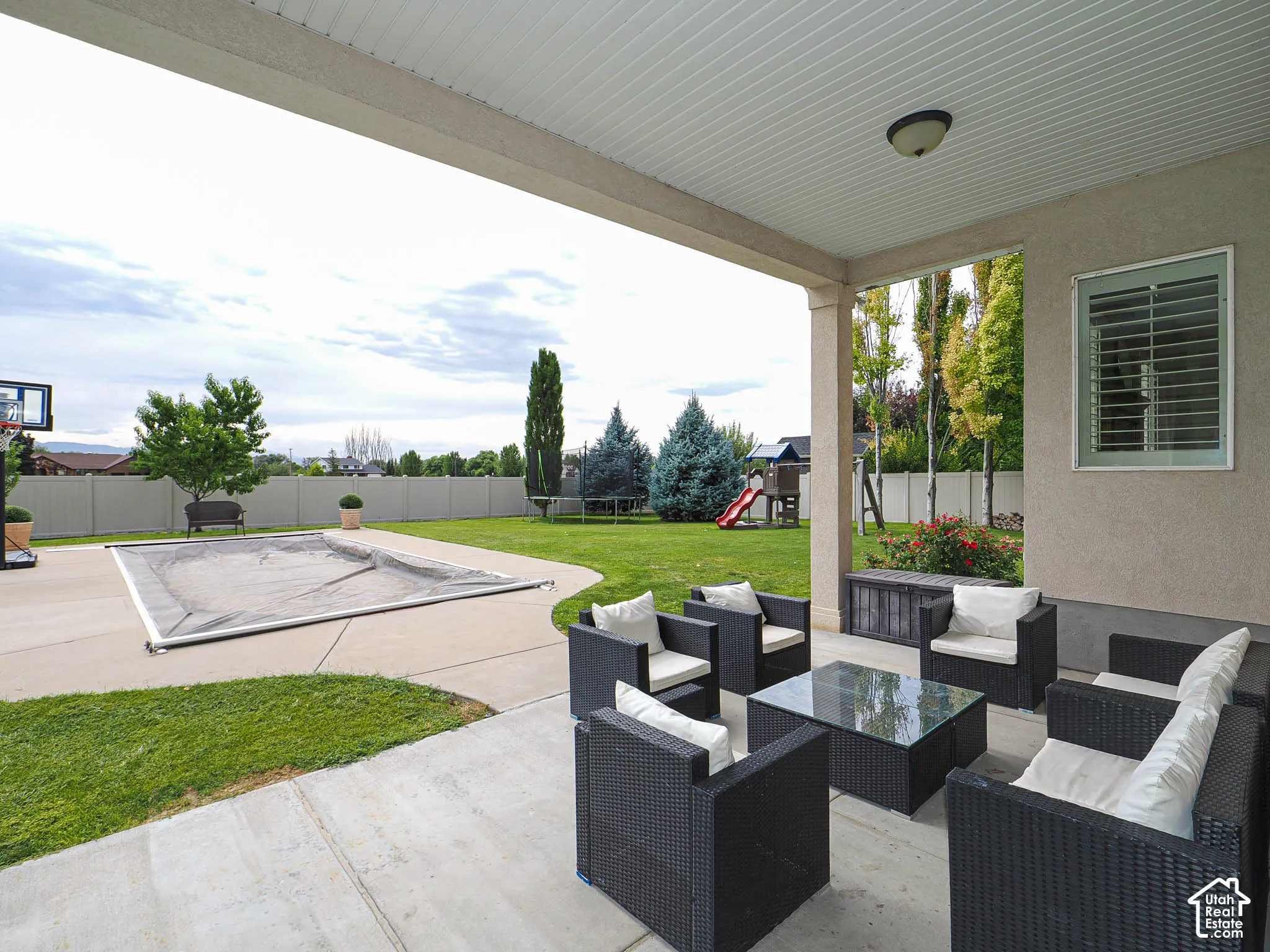 Covered patio with concrete flooring, stucco exterior, and a built-in light fixture