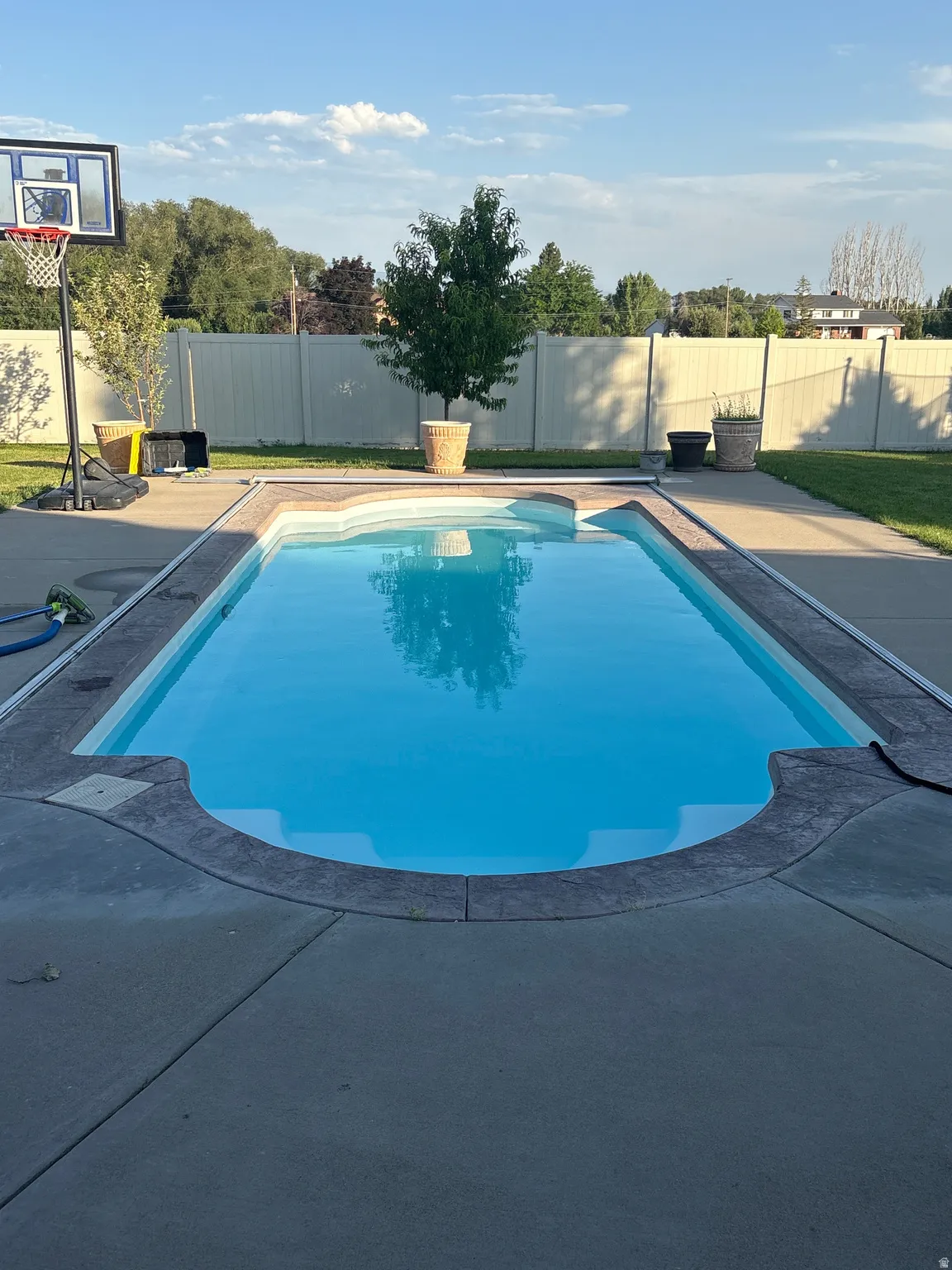 In-ground swimming pool with integrated steps, surrounded by stamped concrete decking