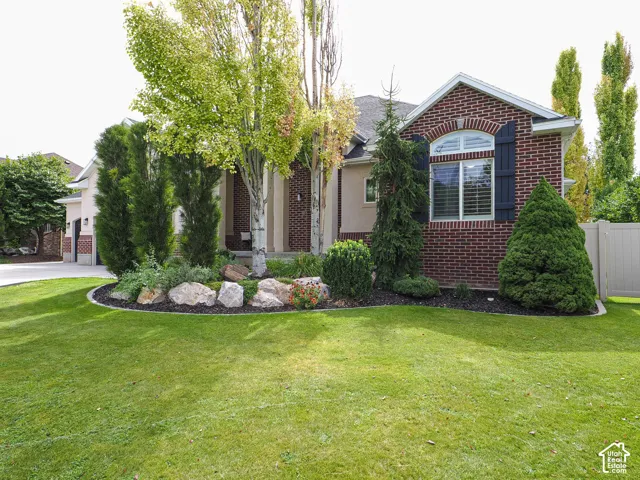 Brick and stucco exterior with an arched window, decorative shutters, and mature landscaping