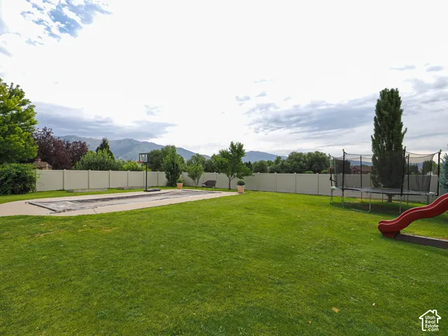 Expansive backyard featuring a manicured lawn, established perimeter fencing, and a hardscaped patio area