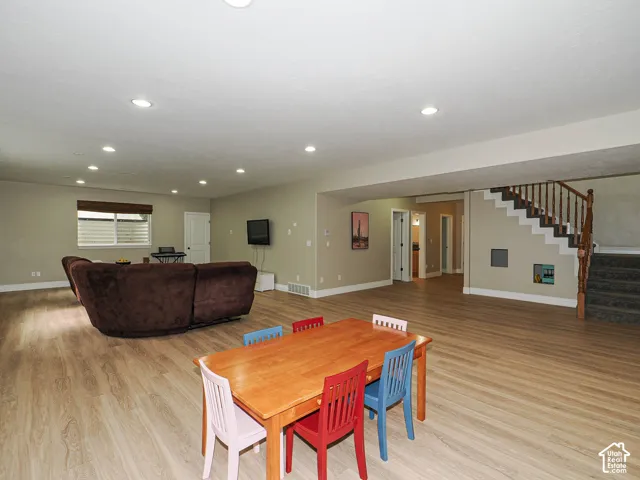 Recessed lighting throughout, wood-finish flooring, staircase with wood banister, built-in window with horizontal blinds, and interior doors
