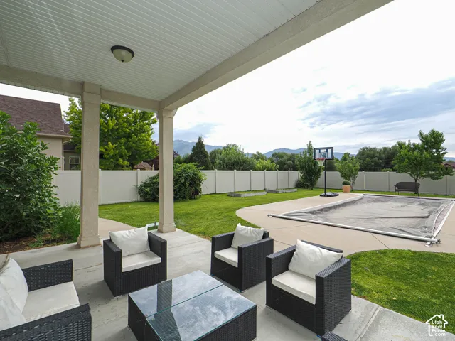 Covered concrete patio with recessed lighting, concrete pool deck, fenced perimeter, and a pool with a cover