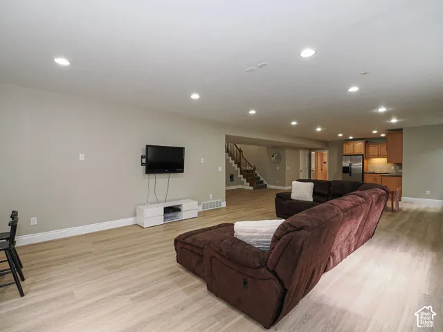 Recessed lighting, light wood-finish flooring, staircase with wood railing, built-in cabinetry, and integrated appliances