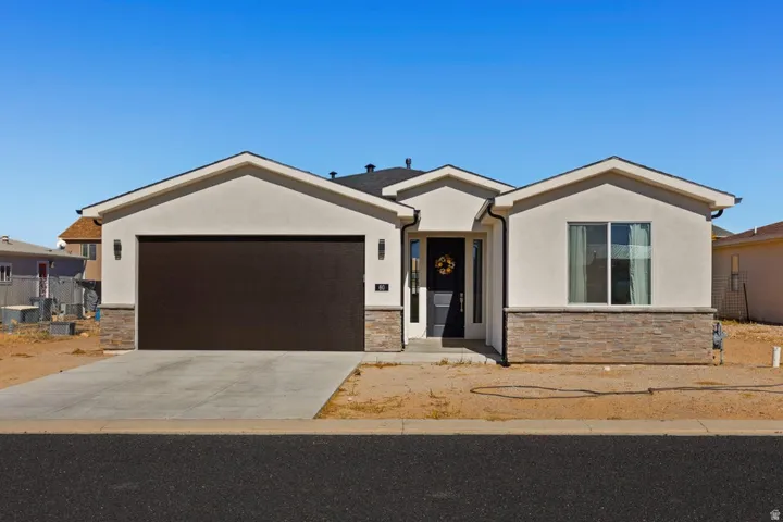 Contemporary stucco exterior with stone accents, covered entry, and attached garage