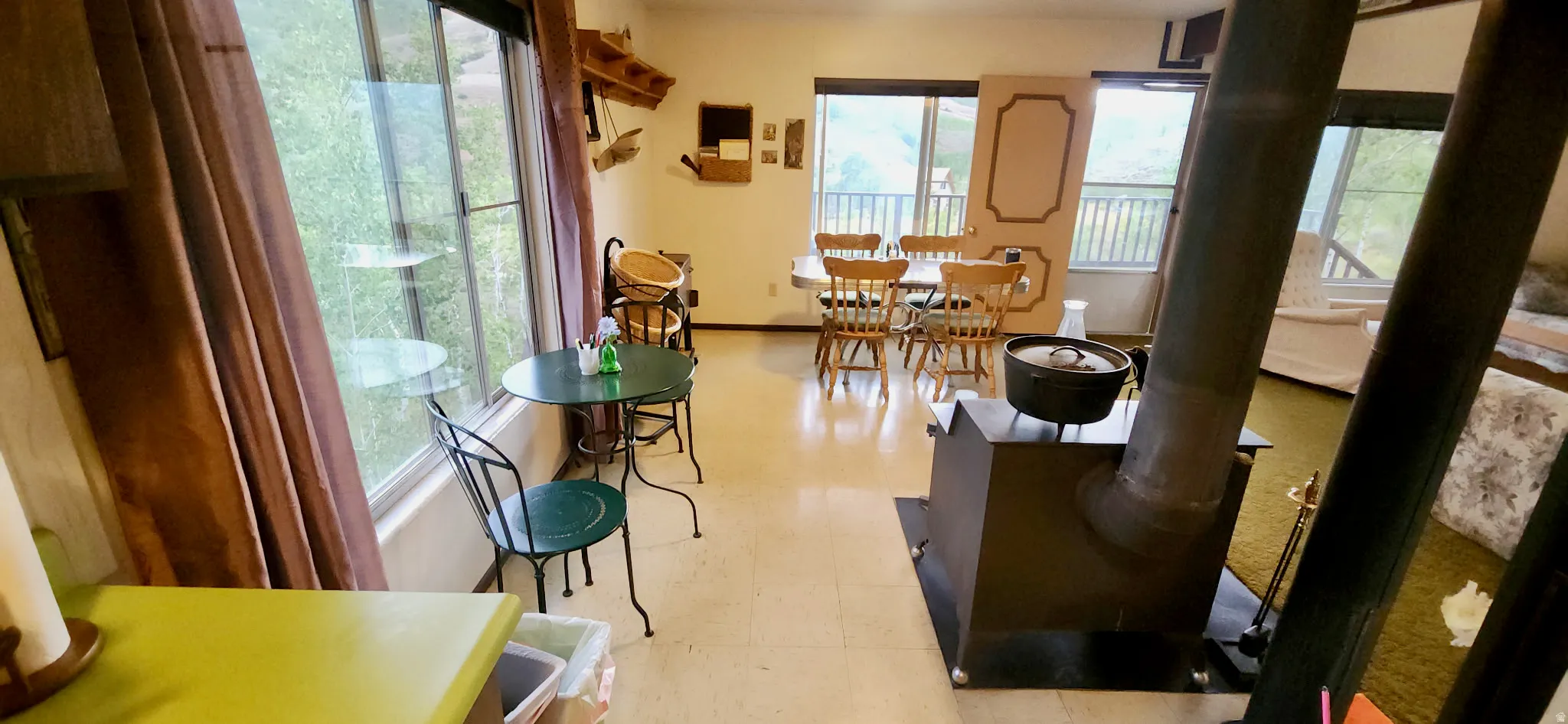 Expansive windows, wood-burning stove, hard surface flooring, and a balcony